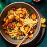 Plate of spaghetti topped with crispy zucchini slices.