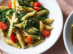 Bowl of penne pasta coated in vibrant green pesto sauce.