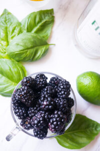 Blackberry basil ricotta pizza with golden crust, creamy white ricotta, fresh blackberries, and green basil leaves on rustic wooden board