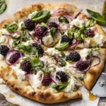 Close-up slice of blackberry basil ricotta pizza showing melted cheese, burst blackberries, and fresh basil garnish