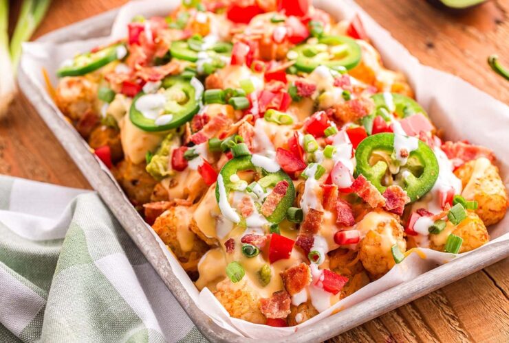 loaded tater tot nachos on large platter with melted cheese, ground beef, jalapeños, and fresh toppings