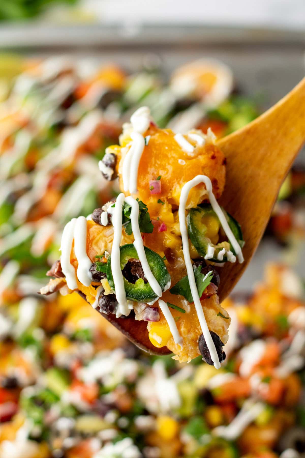 close up shot of loaded tater tot nachos with fork taking a bite showing melted cheese stretch