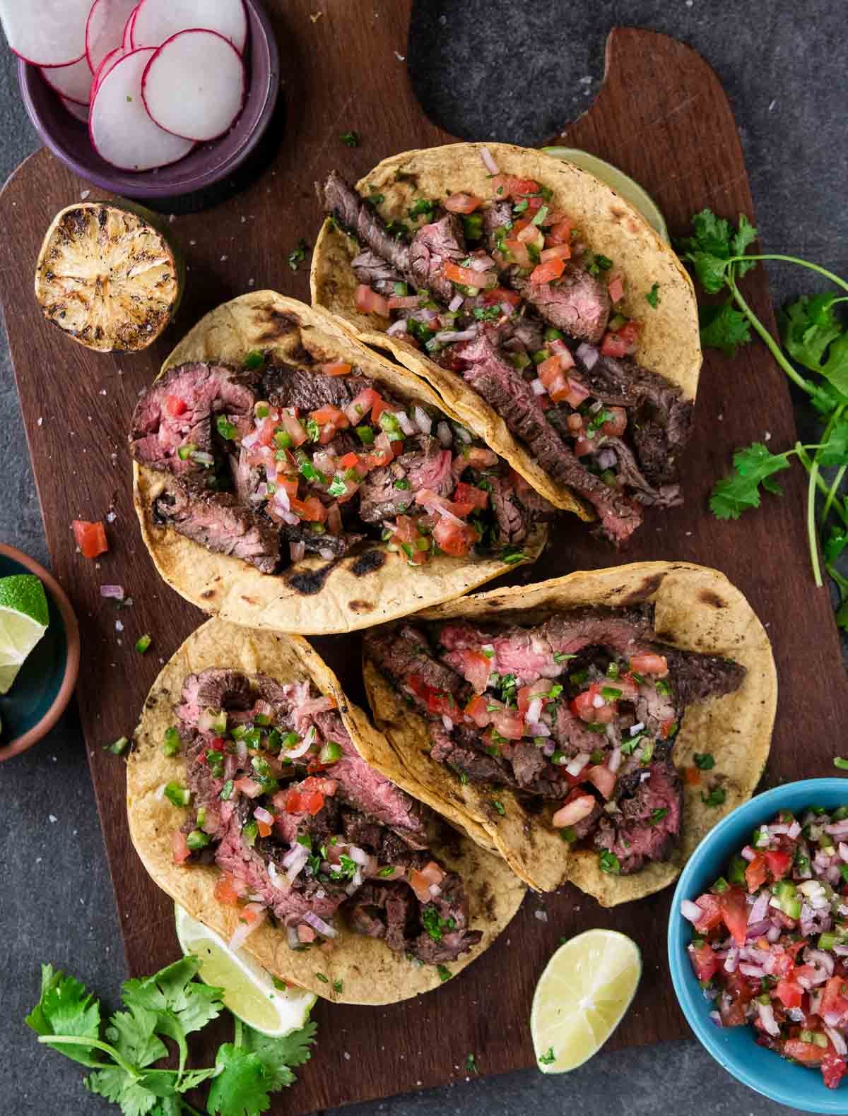 Close-up shot of a perfectly assembled carne asada taco with charred meat, fresh cilantro, and a lime wedge, showing the beautiful contrast of colors and textures