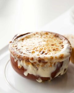 Classic French onion soup in individual crocks topped with golden melted Gruy?re cheese and fresh thyme garnish
