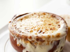 Classic French onion soup in individual crocks topped with golden melted Gruy?re cheese and fresh thyme garnish