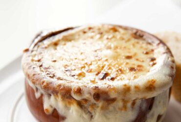 Classic French onion soup in individual crocks topped with golden melted Gruy?re cheese and fresh thyme garnish