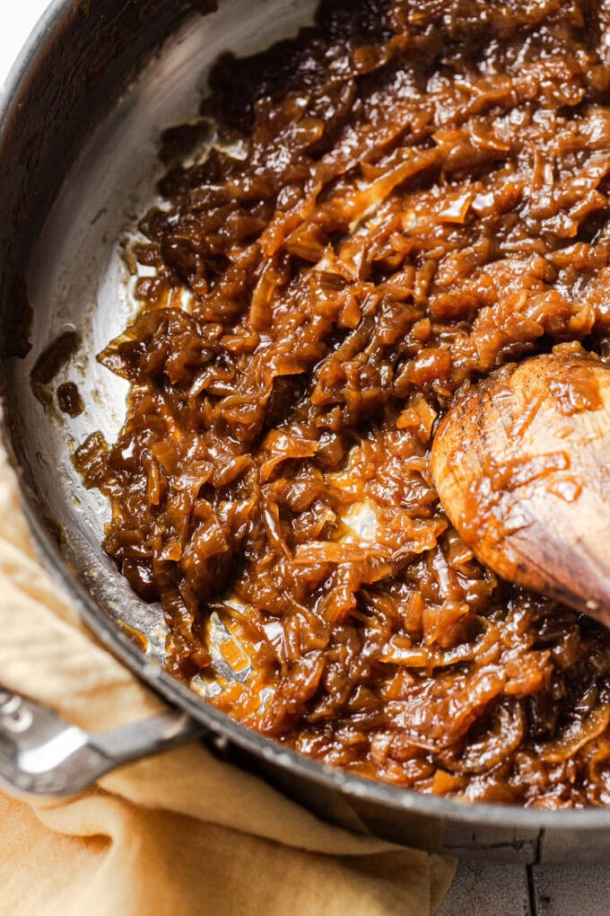 Perfectly caramelized golden-brown onions in a heavy-bottomed pot with wooden spoon