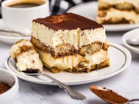 Classic tiramisu in glass dish with cocoa powder dusting and coffee beans scattered around
