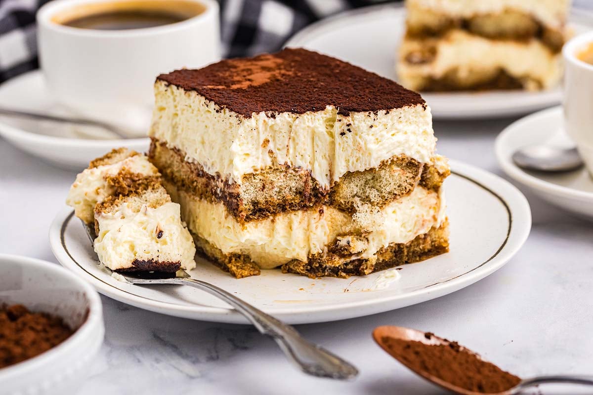 Close-up of tiramisu slice on elegant plate with coffee cup and spoon beside it