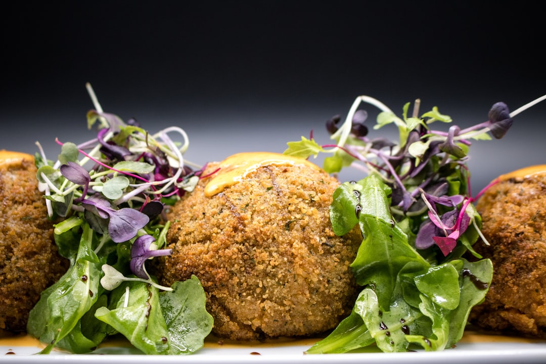 Close-up shot of a halved falafel showing the crispy golden exterior and tender, herb-flecked interior, with tahini sauce drizzled on top