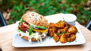 Tender, juicy pulled pork piled high on a brioche bun with coleslaw, served alongside crispy sweet potato fries on a rustic wooden plate