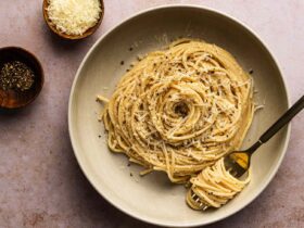 Creamy cacio e pepe pasta in a large skillet with freshly cracked black pepper and grated pecorino romano cheese