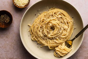 Creamy cacio e pepe pasta in a large skillet with freshly cracked black pepper and grated pecorino romano cheese
