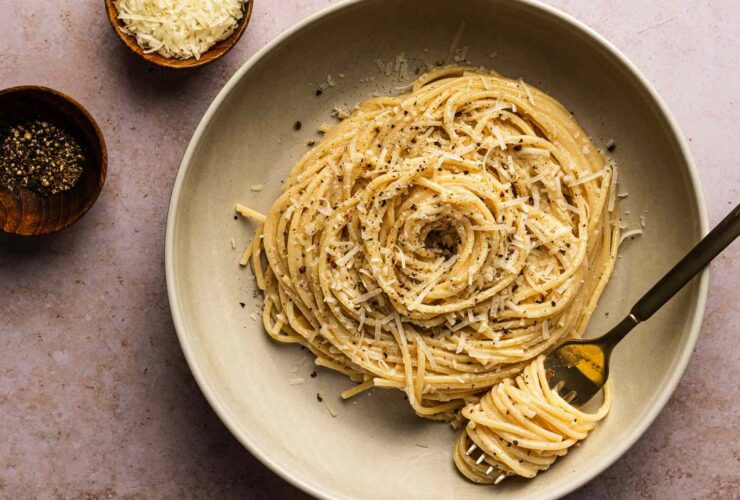 Creamy cacio e pepe pasta in a large skillet with freshly cracked black pepper and grated pecorino romano cheese