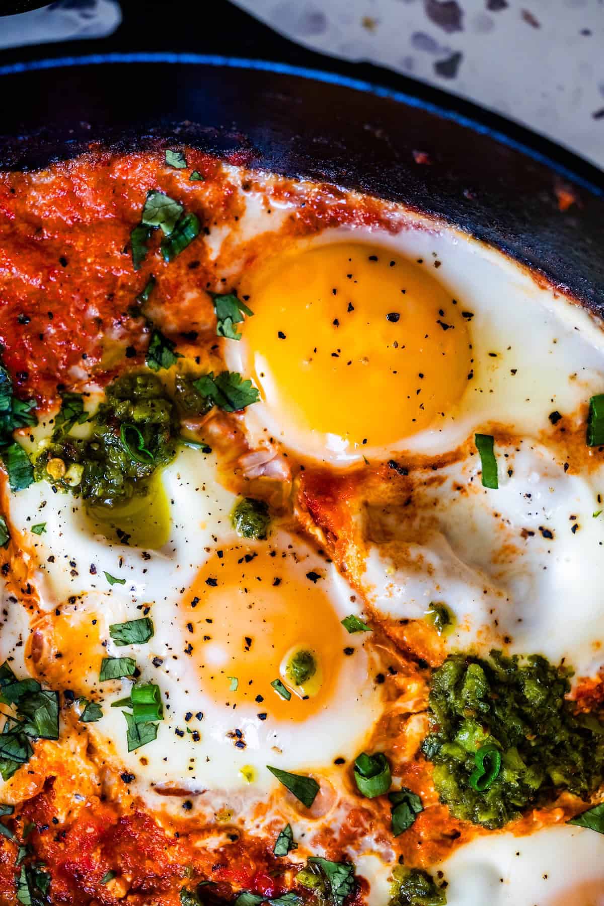 Close-up shot of shakshuka being served with a spoon, showing the creamy egg yolk mixing with the rich tomato sauce, garnished with fresh parsley