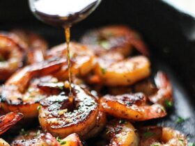 honey glazed shrimp in skillet with golden caramelized sauce and garnished with green onions and sesame seeds