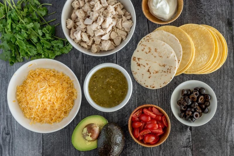 Step-by-step shot showing marinated chicken pieces, colorful diced vegetables, and warm tortillas ready for assembly