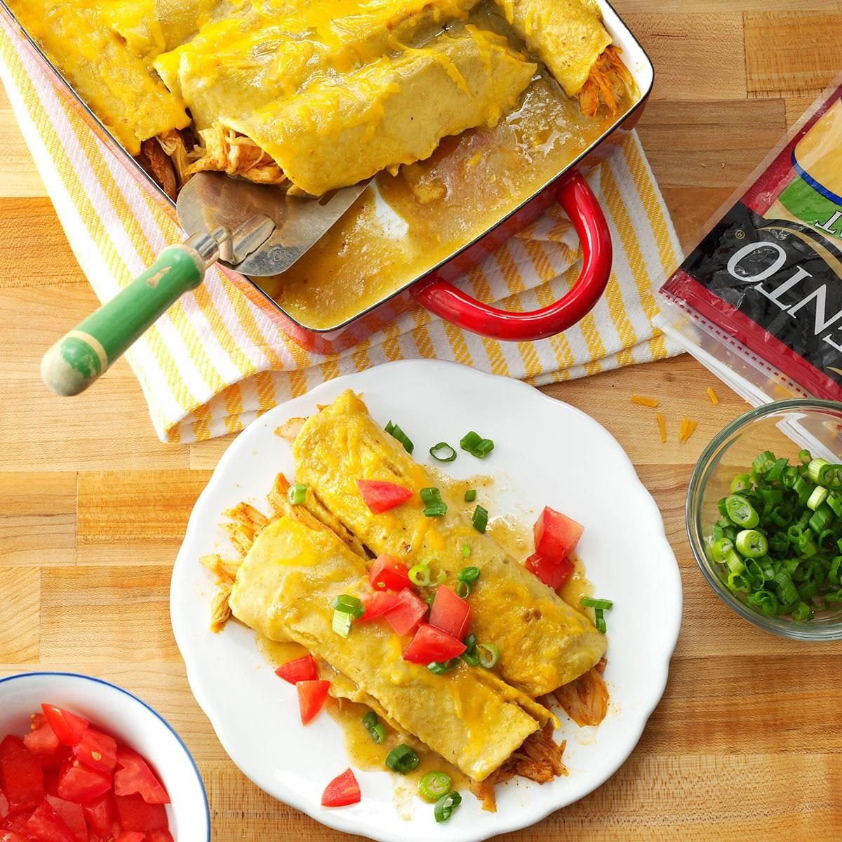 Close-up shot of a cut honey lemon chicken enchilada showing the golden chicken filling, melted cheese, and fresh herb garnish