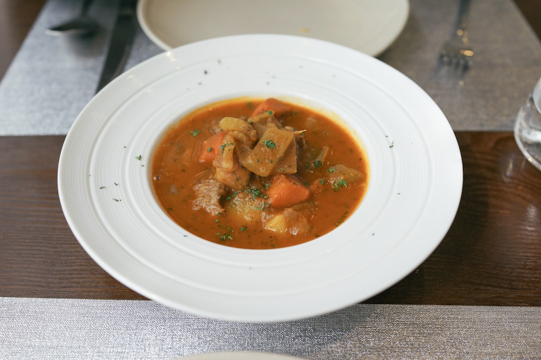 Step-by-step preparation showing diced onions, carrots, and potatoes alongside cubed beef and curry roux blocks on a cutting board
