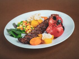 Lebanese kafta kebabs beautifully plated on a white serving platter with grilled vegetables, fresh parsley garnish, and pita bread on the side