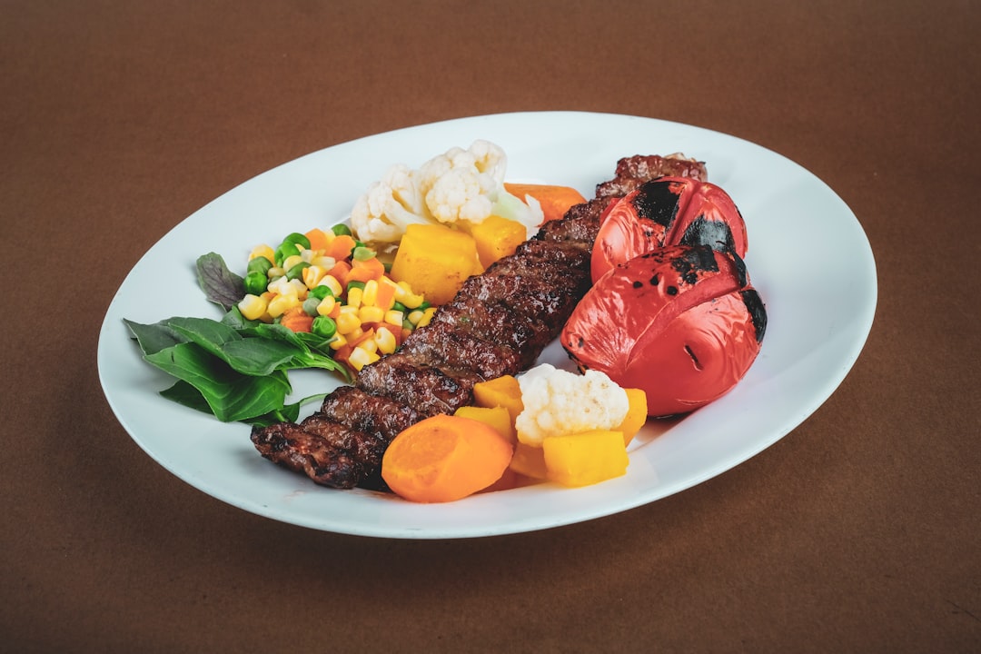 Lebanese kafta kebabs beautifully plated on a white serving platter with grilled vegetables, fresh parsley garnish, and pita bread on the side