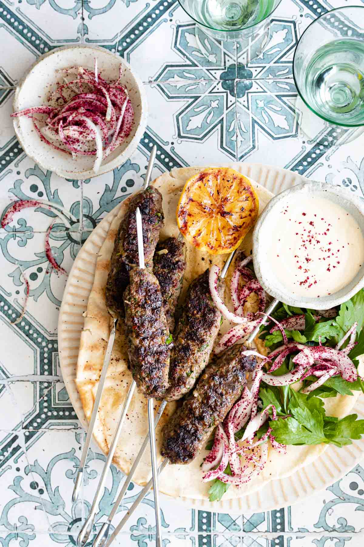 Close-up shot of sliced kafta kebabs showing the tender interior, served alongside rice pilaf and a cucumber yogurt sauce