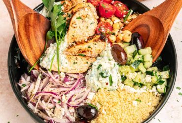 Mediterranean chicken bowl with golden seasoned chicken, fresh vegetables, olives, feta cheese, and creamy tzatziki arranged in a rustic ceramic bowl