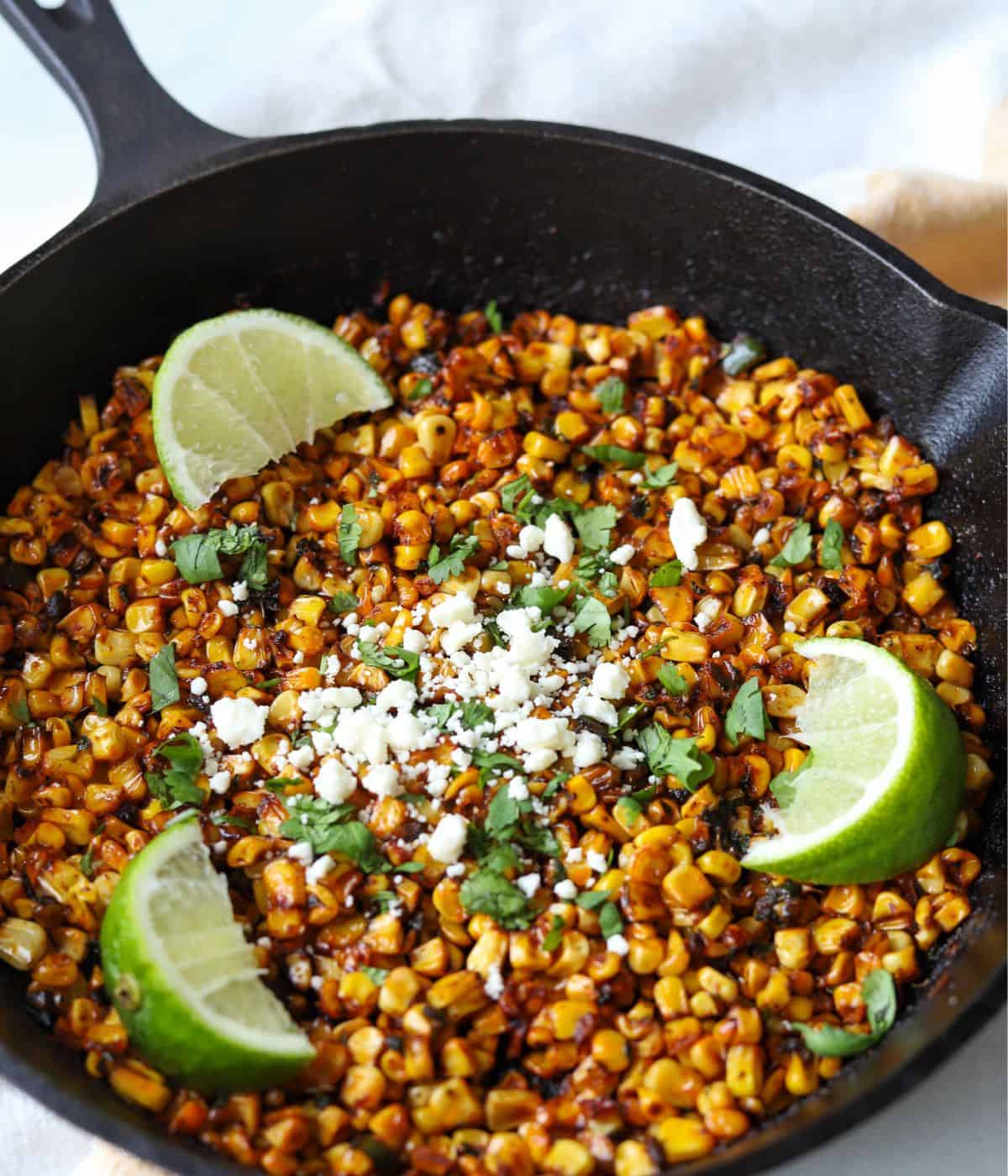 Step-by-step shot showing corn kernels being charred in a cast iron skillet with golden brown spots visible