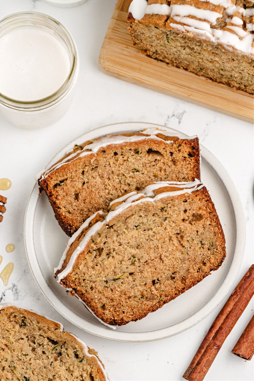 golden brown zucchini bread loaf sliced on wooden cutting board with butter and honey
