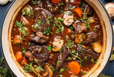 Beef Bourguignon served in a rustic white bowl with tender chunks of beef, mushrooms, and pearl onions in rich burgundy sauce, garnished with fresh thyme