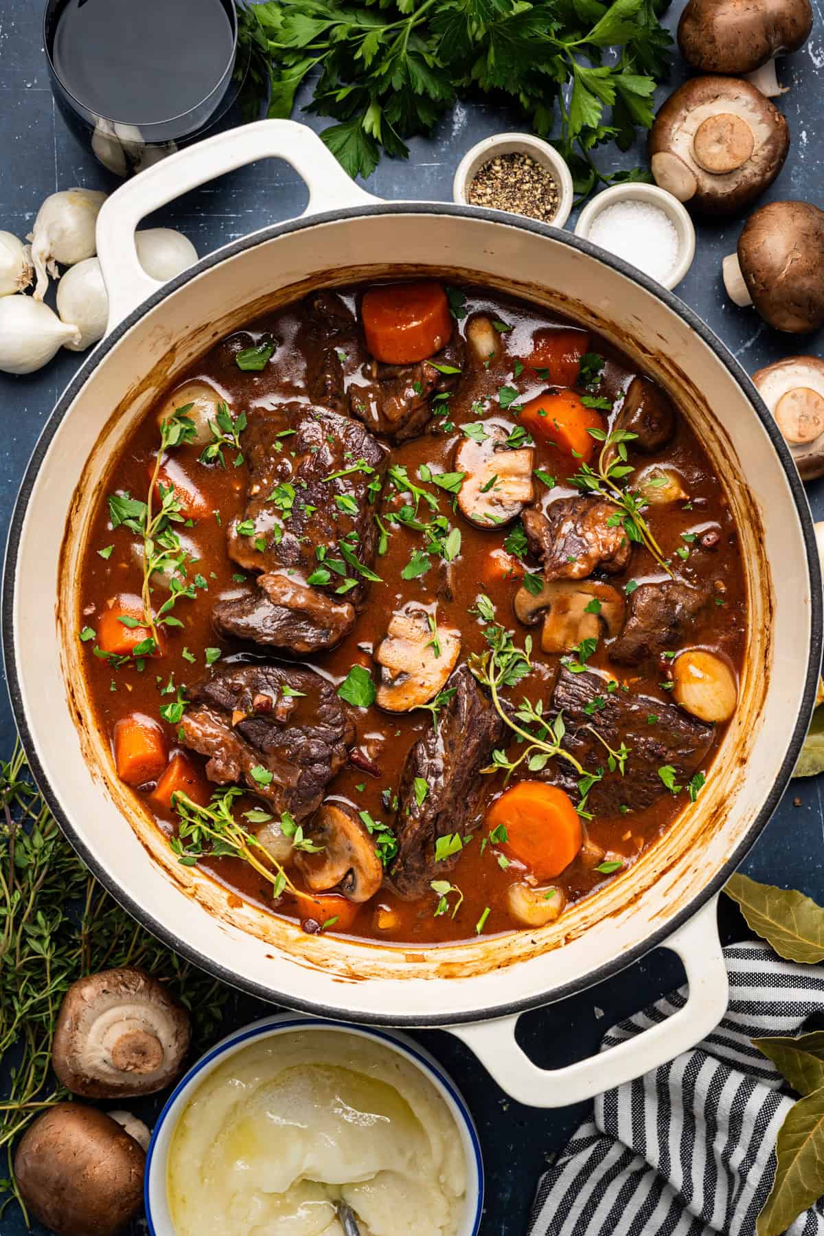 Beef Bourguignon served in a rustic white bowl with tender chunks of beef, mushrooms, and pearl onions in rich burgundy sauce, garnished with fresh thyme