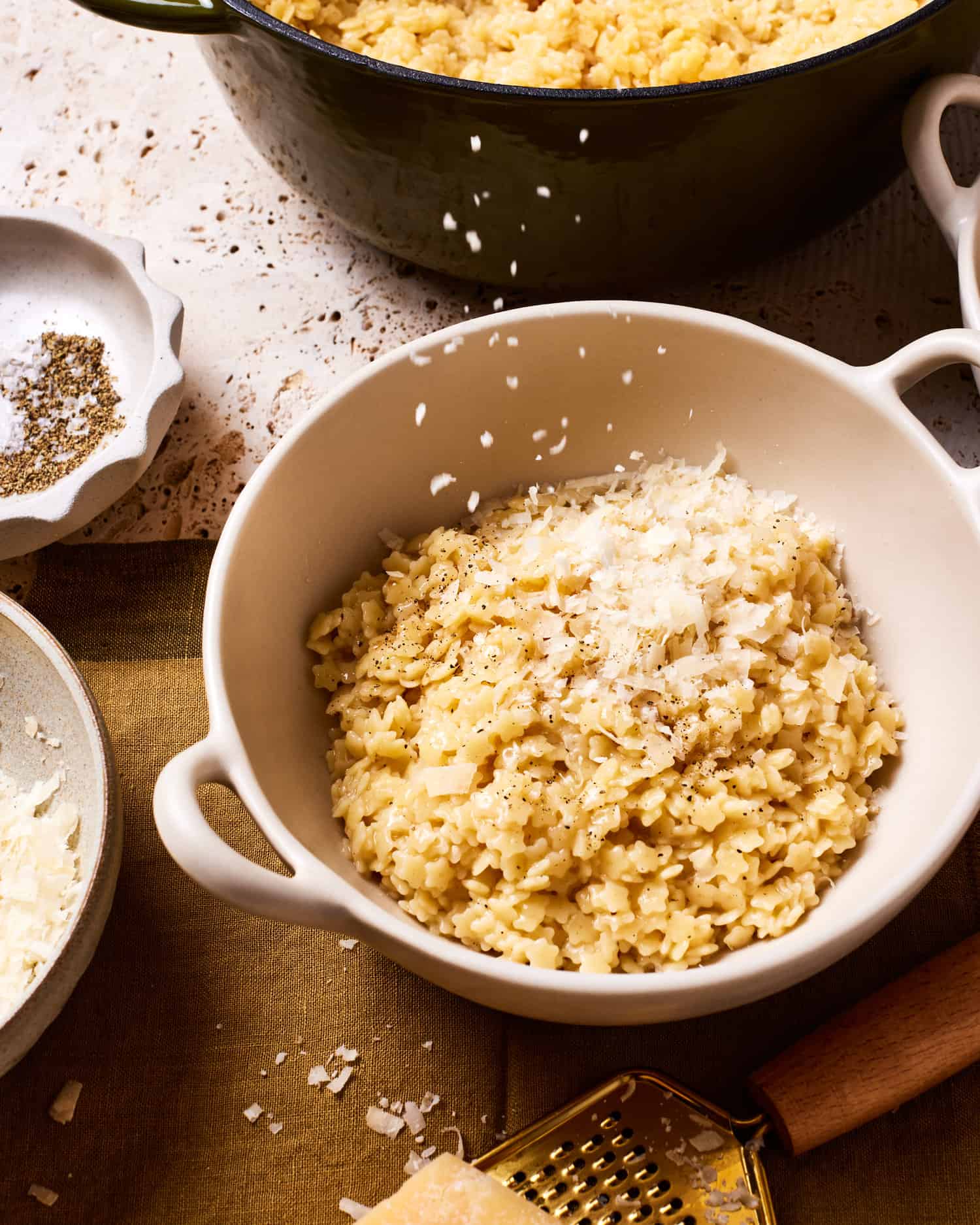 Creamy buttered pastina served in a white ceramic bowl with freshly grated Parmesan cheese and black pepper, garnished with fresh herbs on a rustic wooden table