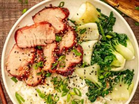 Glossy char siu pork slices arranged on white plate with steamed rice and green onions garnish