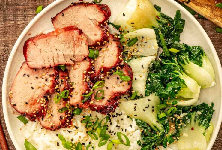 Glossy char siu pork slices arranged on white plate with steamed rice and green onions garnish