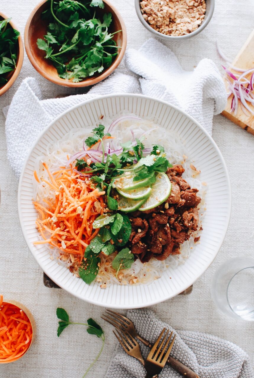 Raw pork strips in marinade in glass bowl with ingredients laid out around it