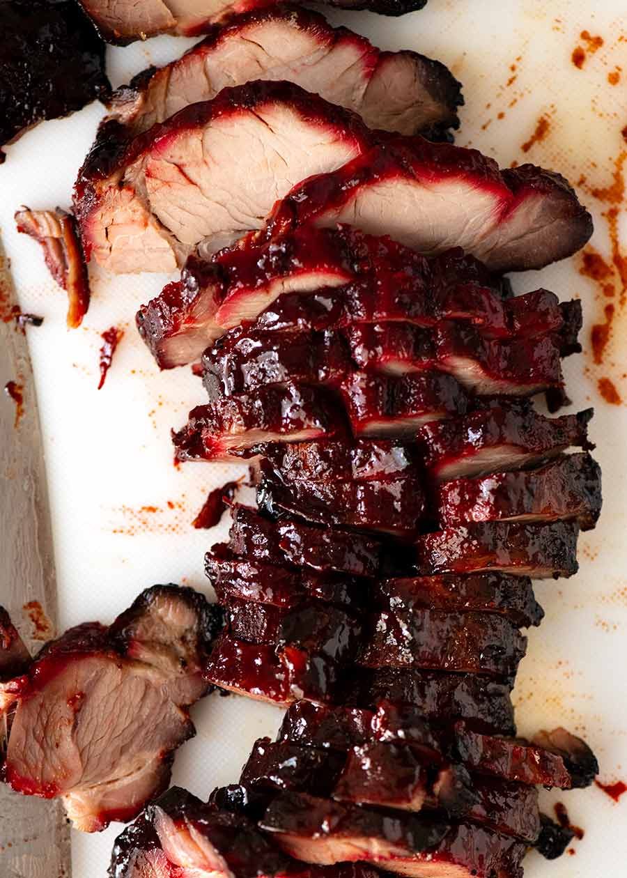 Close-up of sliced char siu pork showing caramelized edges and juicy interior with chopsticks