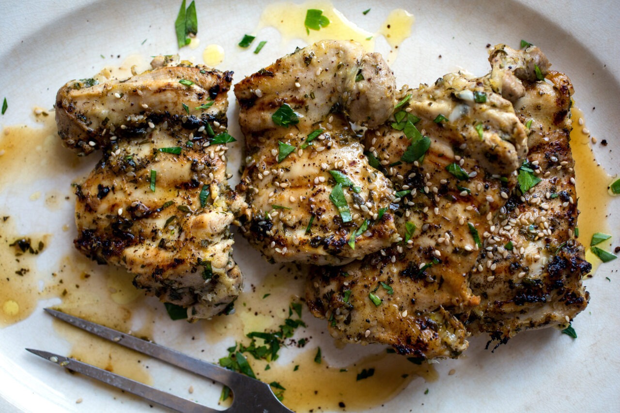 Raw marinated chicken thighs in a bowl showing the colorful spice coating