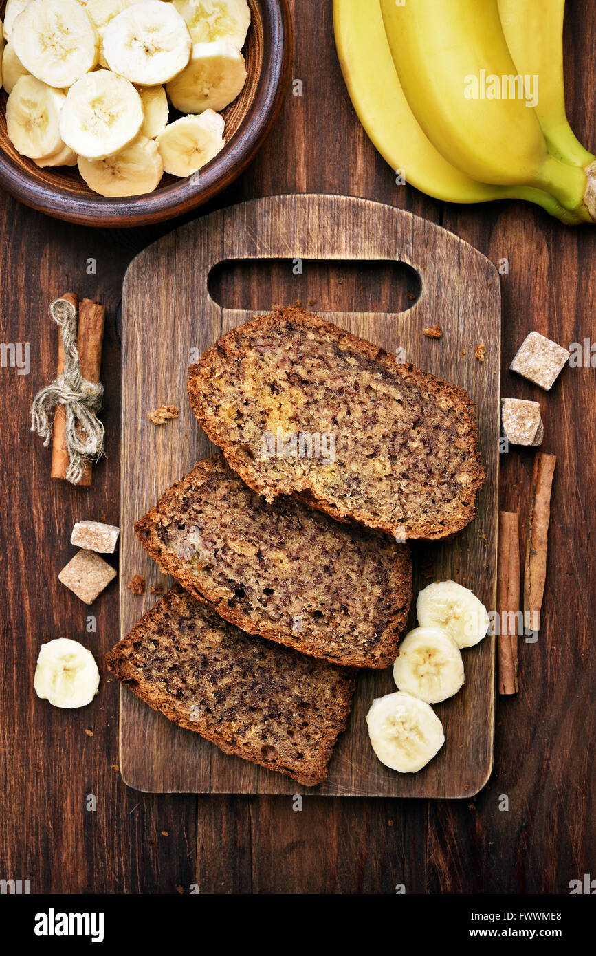 Golden brown banana bread loaf sliced on a wooden cutting board with butter and a knife nearby, natural lighting showing the moist, tender crumb