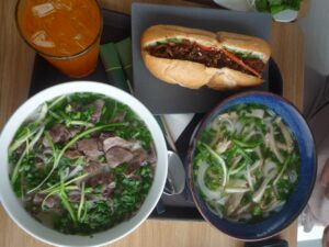 Colorful banh mi sandwiches with crispy bread, pickled vegetables, fresh herbs, and golden protein filling arranged on a wooden cutting board