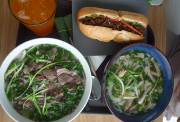 Colorful banh mi sandwiches with crispy bread, pickled vegetables, fresh herbs, and golden protein filling arranged on a wooden cutting board