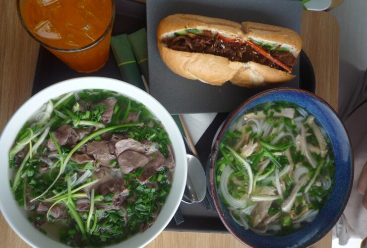 Colorful banh mi sandwiches with crispy bread, pickled vegetables, fresh herbs, and golden protein filling arranged on a wooden cutting board
