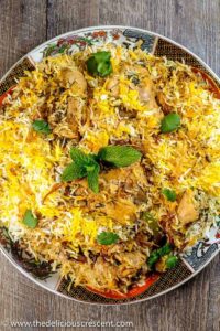Overhead shot of chicken biryani in a large pot with golden rice, tender chicken pieces, and fresh herbs garnish
