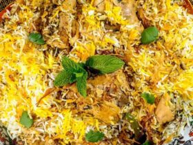 Overhead shot of chicken biryani in a large pot with golden rice, tender chicken pieces, and fresh herbs garnish