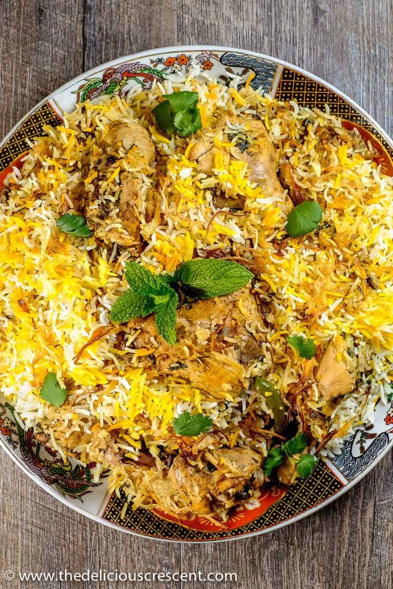 Overhead shot of chicken biryani in a large pot with golden rice, tender chicken pieces, and fresh herbs garnish