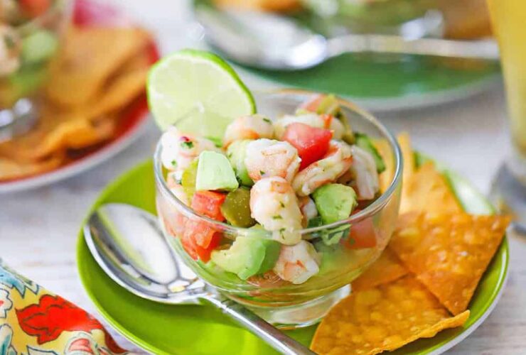 Fresh shrimp ceviche served in a large glass bowl with colorful diced vegetables, garnished with cilantro and served with tortilla chips