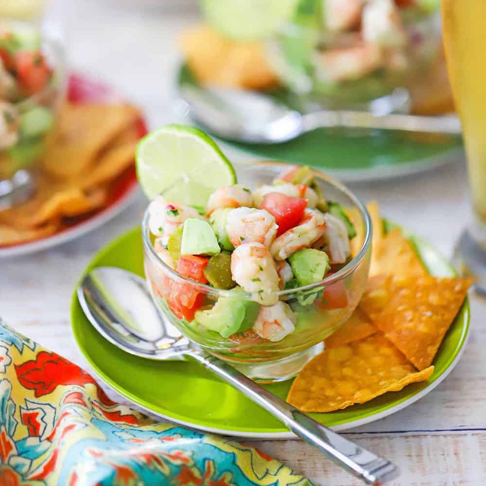 Fresh shrimp ceviche served in a large glass bowl with colorful diced vegetables, garnished with cilantro and served with tortilla chips