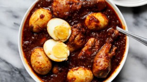 Ethiopian Doro Wat served in a traditional clay pot with hard-boiled eggs visible, garnished with fresh herbs, with injera bread on the side