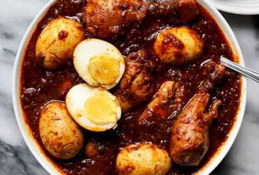 Ethiopian Doro Wat served in a traditional clay pot with hard-boiled eggs visible, garnished with fresh herbs, with injera bread on the side