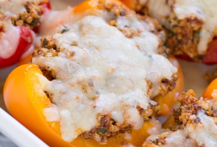 Colorful stuffed bell pepper boats filled with ground turkey quinoa and Mediterranean herbs on a white serving platter, garnished with fresh parsley and crumbled feta
