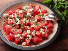 Colorful watermelon feta mint salad in a white serving bowl with fresh mint garnish on a rustic wooden table